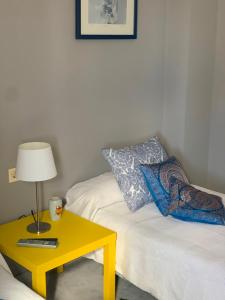 a living room with a yellow table and a bed at Ático Romano in Estepona