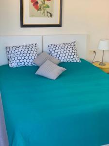 a blue bed with two pillows on top of it at Ático Romano in Estepona