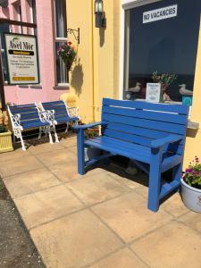 dois bancos azuis sentados do lado de fora de um edifício em Awel Mor em Criccieth