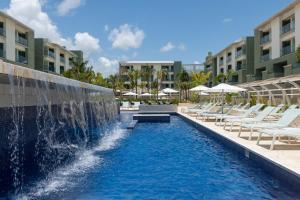 a swimming pool with chairs and a fountain at a resort at Catalonia Grand Costa Mujeres All Suites & Spa - All Inclusive in Cancún