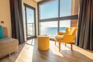 a living room with a yellow chair and a large window at MAIA Luxury Beach Hotel & Spa in Guzelcamlı