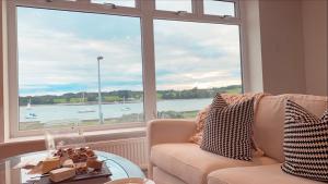 een woonkamer met een bank en een groot raam bij New home with stunning views of the Menai Straits in Llanedwen