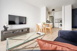 a living room with a glass coffee table and a tv at Apartament Dwa Jeziora in Olsztyn