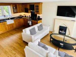 een woonkamer met 2 witte banken en een open haard bij New home with stunning views of the Menai Straits in Llanedwen