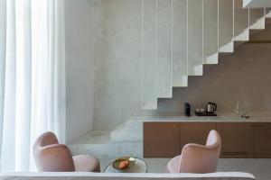 ein Wohnzimmer mit 2 Stühlen und einer Treppe in der Unterkunft Mirabile Luxury Suites in Chania