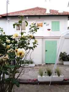 una casa blanca con una puerta verde y flores en El Abuelo Paco, en Cercedilla