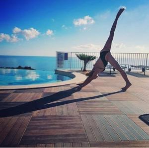 a woman doing a pose in front of a swimming pool at Hotel Antica Cascina Del Golfo in Scopello