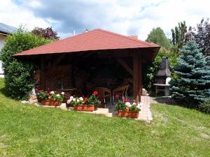a wooden gazebo with flowers in a yard at Penzion Cabák in Vrchlabí