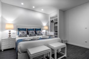een witte slaapkamer met een groot bed met blauwe kussens bij Ilheu 25 Peniche House in Peniche