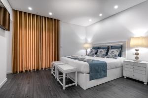 een witte slaapkamer met een groot bed en een raam bij Ilheu 25 Peniche House in Peniche