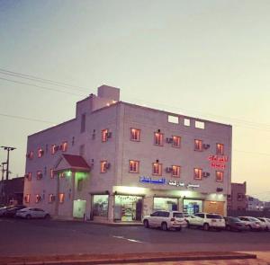 Al ‘Aqīqأماسي الواحة للشقق المخدومة的一座大楼，前面停满了汽车