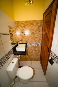 a bathroom with a white toilet and a sink at Pousada Sena in Flecheiras