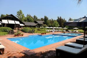 uma grande piscina com cadeiras e guarda-sóis em La Posta del Pilar Hotel & Spa em Pilar