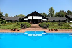 a swimming pool in front of a house with a building at La Posta del Pilar Hotel & Spa in Pilar
