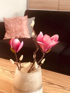 een vaas met roze bloemen op een tafel bij Apartament Matejki II - Unique Apartments in Szczecin