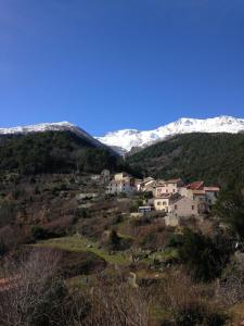 een dorp op een heuvel met besneeuwde bergen bij A.Casetta in Santo-Pietro-di-Venaco