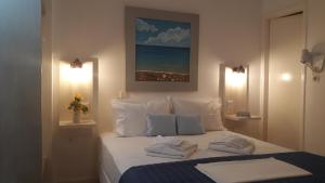 a bedroom with a bed with white sheets and pillows at Katerina Rooms in Tinos Town