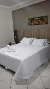 ein großes weißes Bett mit weißer Bettwäsche und Kissen in der Unterkunft Hotel Ravenna in Divinópolis