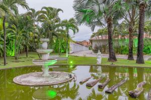 a fountain in the middle of a pond with palm trees at Dreams Motel (Adult Only) in Fortaleza
