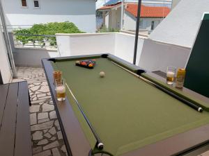 a pool table on a balcony with two glasses of beer at Villa Linda in Ražanj