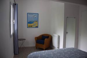 een slaapkamer met een bed, een stoel en een foto bij Dokaetchea in Urrugne