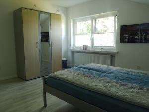 a bedroom with a bed and a cabinet and two windows at Ferienwohnung "In de Ühl" in Hürtgenwald