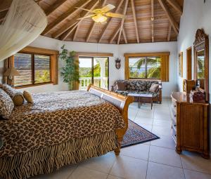 ein großes Schlafzimmer mit einem Leoparden-Bett und einem Sofa in der Unterkunft TAMAR VILLA in Virgin Gorda