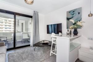 ein weißes Wohnzimmer mit einem Tisch und einem TV in der Unterkunft by RIVA - Cozy, Contemporary Studio in Puerto Banus Gardens in Marbella