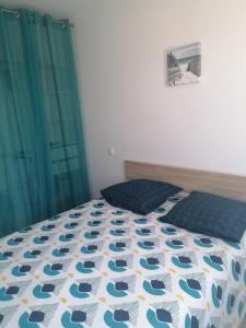 a bedroom with a bed with a blue and white comforter at La gravière in Saint-Geours-de-Maremne