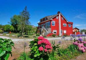 a large red house with flowers in front of it at Pensión Casa Elena in Reinante