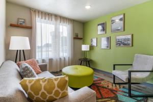 a living room with green walls and a couch and chairs at WoodSpring Suites Austin Georgetown in Georgetown