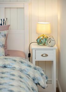 a bed with a nightstand with a lamp and a clock at Sea View Studio Apartments by the Beach in Ihasalu