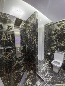 a bathroom with a toilet and a black marble wall at Family Inn Apartments&suites in Neos Marmaras