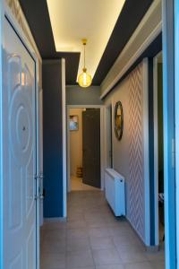 einen Flur mit blauen Wänden und eine Tür mit Fliesenboden in der Unterkunft Family Inn Apartments&suites in Neos Marmaras
