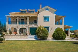 a villa with a large house with a blue sky at Eleni's Family Villa in Laganas