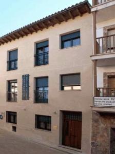 un grand bâtiment avec des fenêtres noires et une porte dans l'établissement Apartamentos Rurales La Vera, à Jarandilla de la Vera