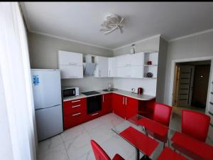 a kitchen with red cabinets and red chairs at Apartments Lutsdorf in Odesa