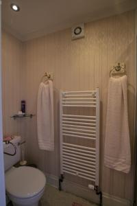 a bathroom with a toilet and towels on the wall at Dunallan Guest House in Perth