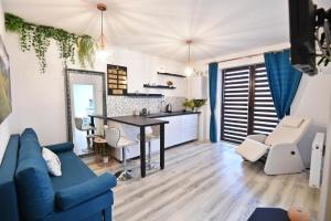 Good Vibes Apartament في براشوف: غرفة معيشة مع أريكة زرقاء ومطبخ