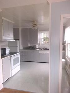 a kitchen with white appliances and a white tile floor at La Maison Vaillancourt in Saint-Laurent-de-l'ile d'Orleans