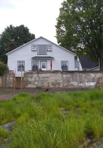 a white house with a red door and a wall at La Maison Vaillancourt in Saint-Laurent-de-l'ile d'Orleans