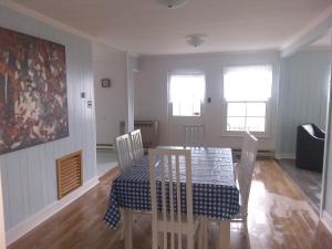 a dining room with a table and chairs and two windows at La Maison Vaillancourt in Saint-Laurent-de-l'ile d'Orleans