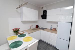 una cucina bianca con armadi bianchi e frigorifero bianco di Apartament Cukrownia a Stettino