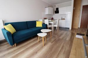 a living room with a blue couch and a table at Apartament Cukrownia in Szczecin