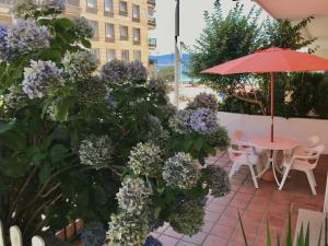 サンシェンショにあるApartamento Sanxenxo Playa Silgar 30mの紫の花と傘付きのテーブルが備わるパティオ