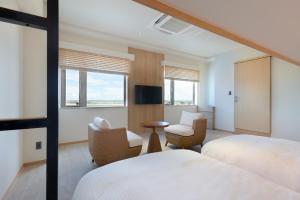 石垣島にあるTHIRD石垣島のベッド2台、椅子、窓が備わるホテルルームです。