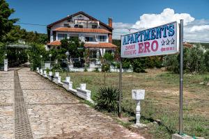 un panneau devant une maison avec un bâtiment dans l'établissement Guest House Ero, à Sukošan