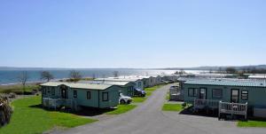 uma fila de casas móveis estacionadas junto à água em Wigbay Loch View 28 em Kirkcolm