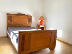 een slaapkamer met een houten bed en een tafel met een lamp bij Spacieuse maison dans un parc privée in Vareilles