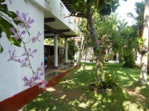 un edificio con flores púrpuras a su lado en White Bridge House & Resort en Aluthgama